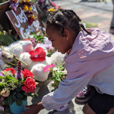 A child placing flowers at the George Floyd memorial